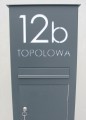 Pionowa skrzynka na listy - wysoki słupek z domofonem i napisem